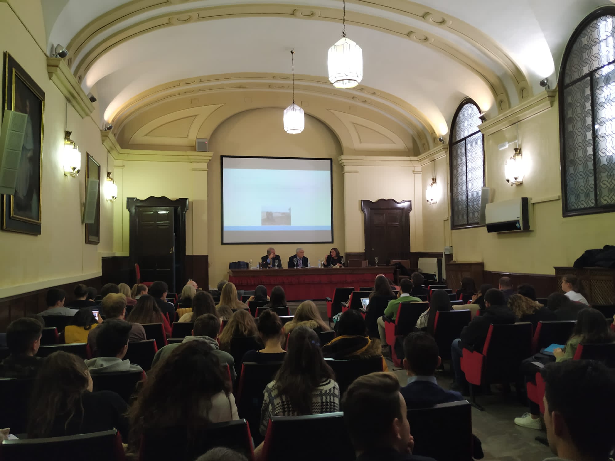 Image taken from the back of the room where you can see the intervention of professors Roldán Barbero and Fernández Arribas