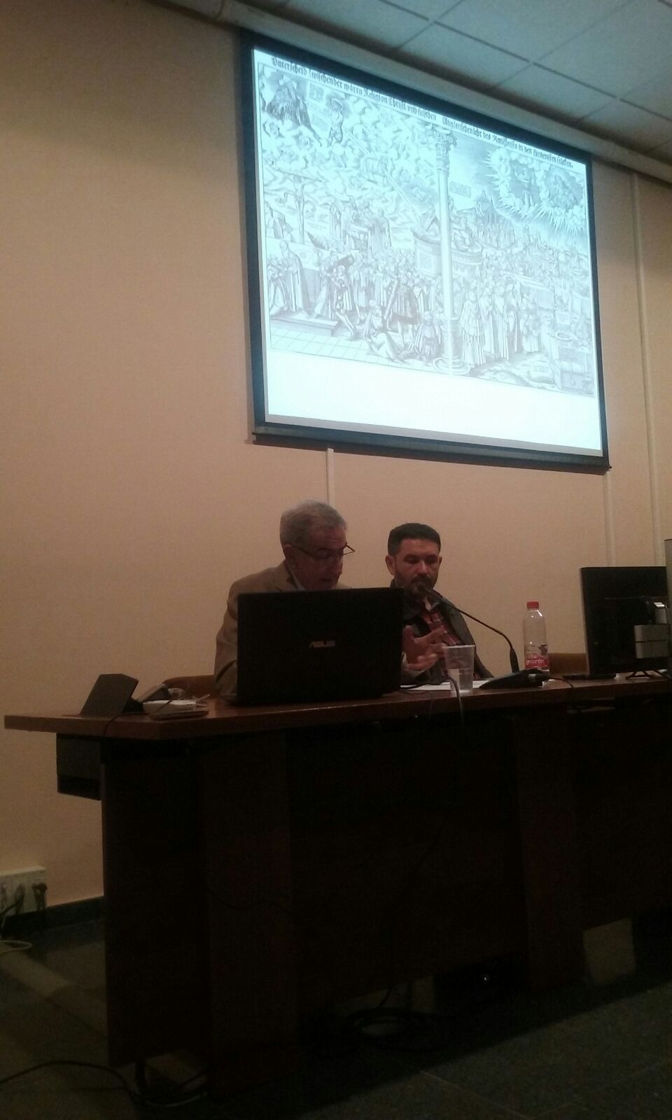Imagen en la que se pueden ver a los ponentes Diego Molina Molina y Serafín Béjar sentados durante el desarrollo de la conferencia