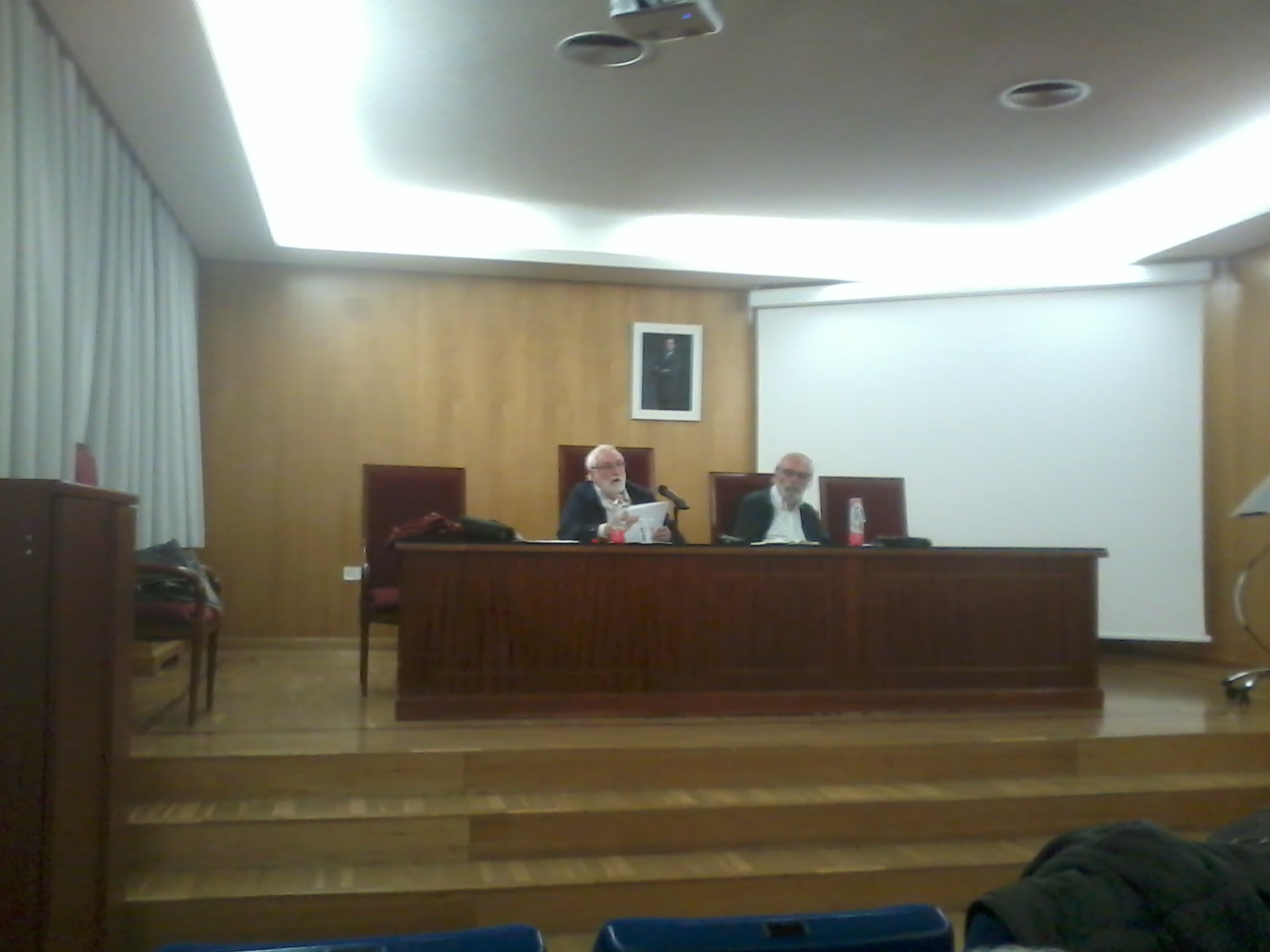 Imagen en la que se pueden ver los profesores Ildefonso Camacho y Javier Elzo sentados durante el desarrollo de la conferencia