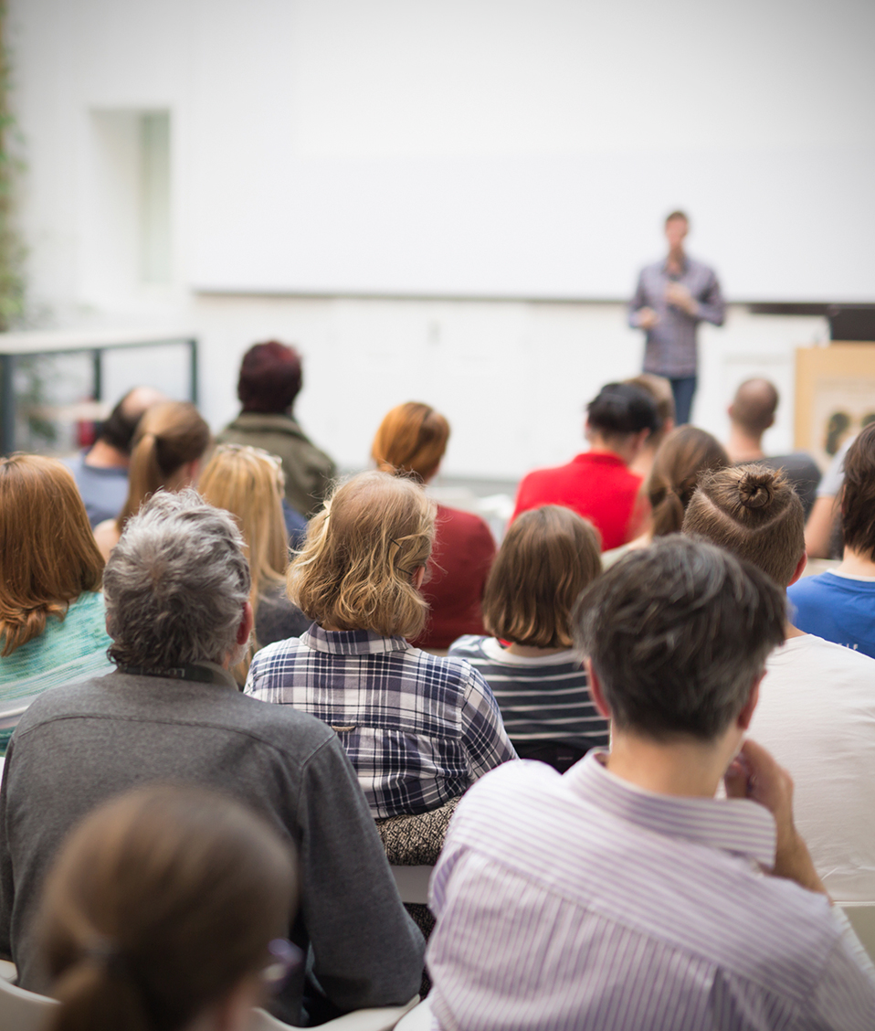 Diversas personas toman nota y atienden desde sus asientos a la exposición de un conferenciante