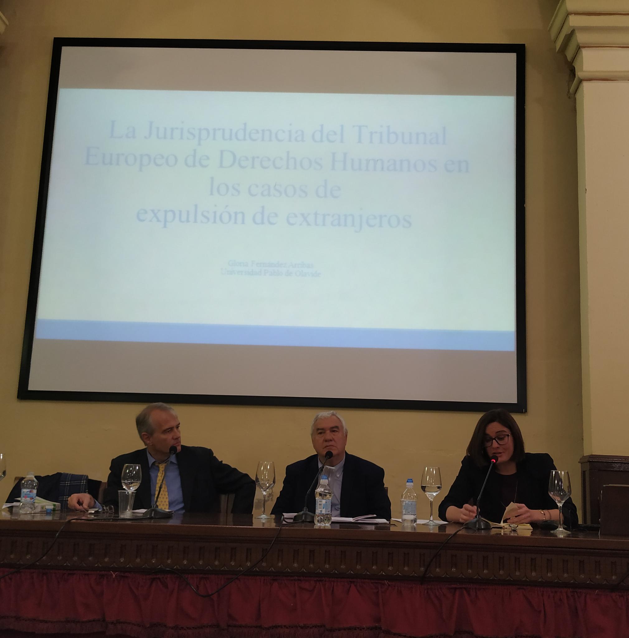Imagen en la que se puede apreciar la intervención de los profesores Roldán Barbero y Fernández Arribas, detrás de ellos hay una pantalla de proyección